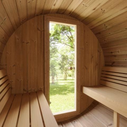 Inside view of the SaunaLife 4-Person Barrel Sauna Kit, looking out through the partially open front glass door, highlighting the inviting and cozy interior ambiance