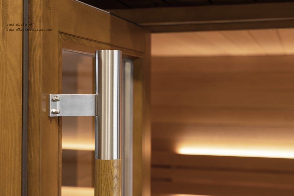 Close-up view of the substantial natural Oak and stainless steel door handle on the SaunaLife Model G7, showcasing its exceptional craftsmanship and robust design.