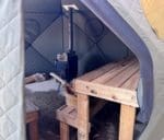 Two benches and wood stove in outdoor sauna tent